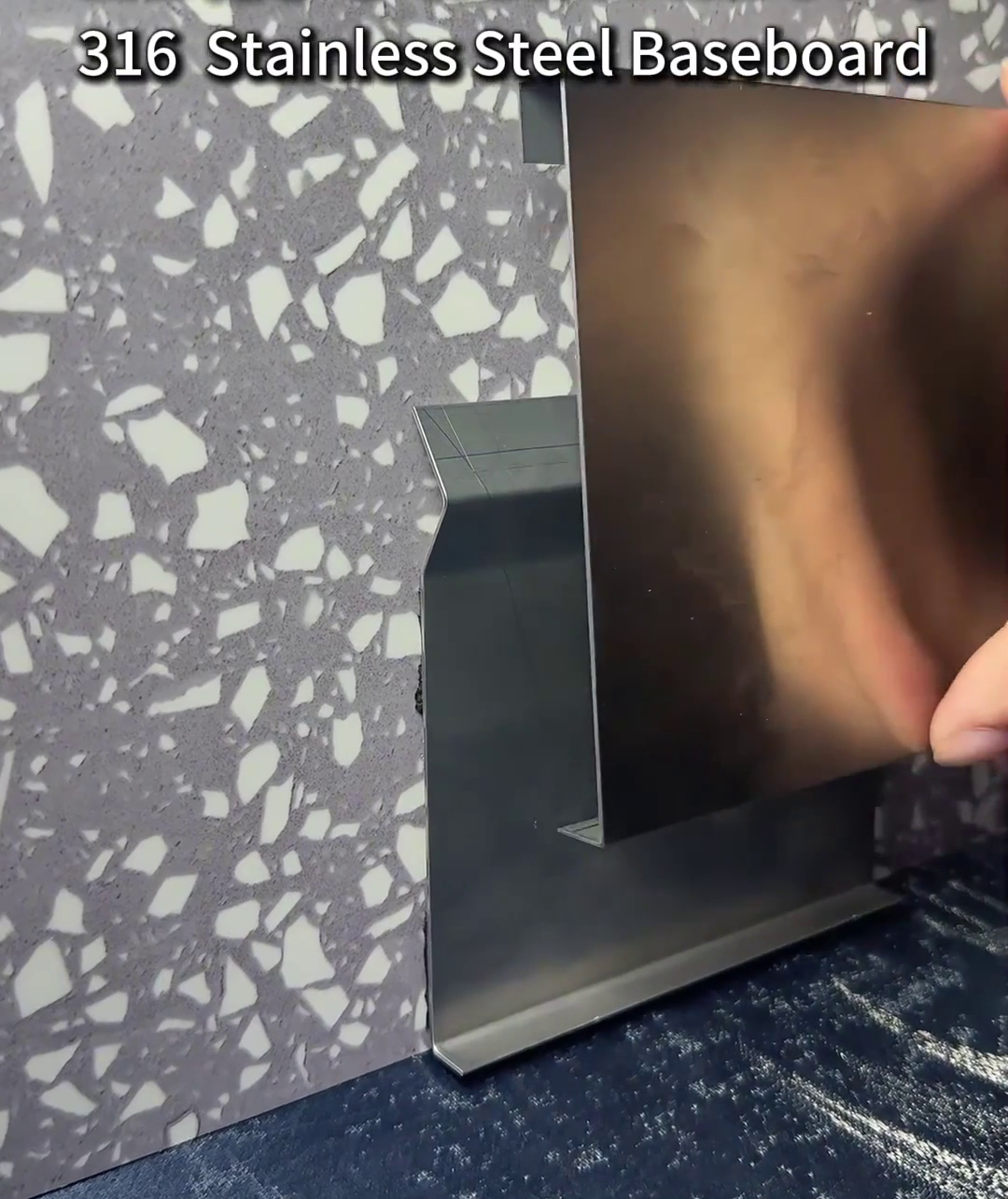 Close-up of a 316 stainless steel baseboard profile being installed on a terrazzo wall