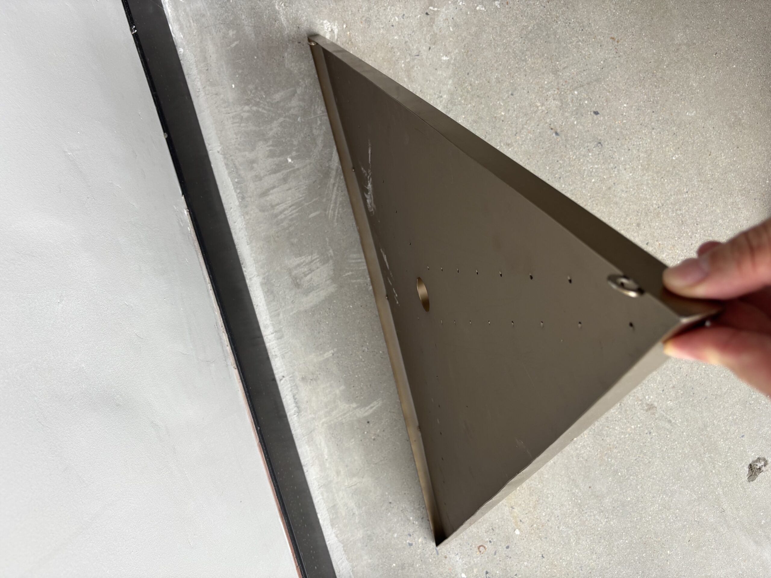 Close-up of stainless steel honeycomb panel edge with pre-drilled rivet holes for hidden mounting.