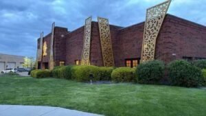 Vertical brushed gold laser-cut stainless steel facade panels in front of a brick commercial building