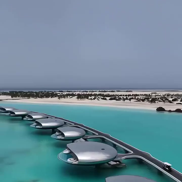 Mirror-finish stainless steel pod villas on Red Sea lagoon at dusk