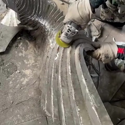 Polishing the spiral ribs of a stainless steel sculpture with an angle grinder