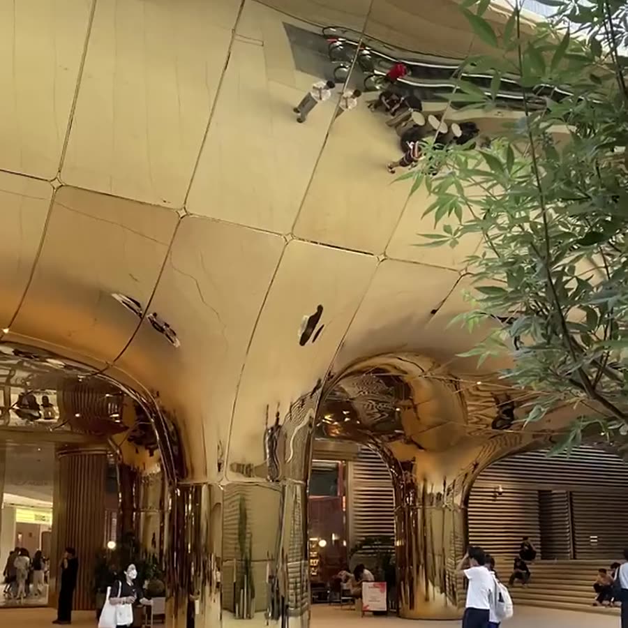 Champagne-gold mirror stainless steel ceiling canopy formed from diamond-pattern panels above arched mall columns, with recessed spotlights