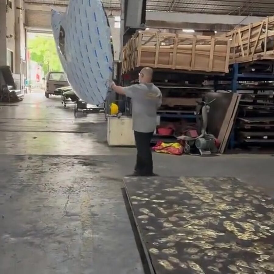 ARTDSN worker handling a large mirror-polished stainless steel facade panel