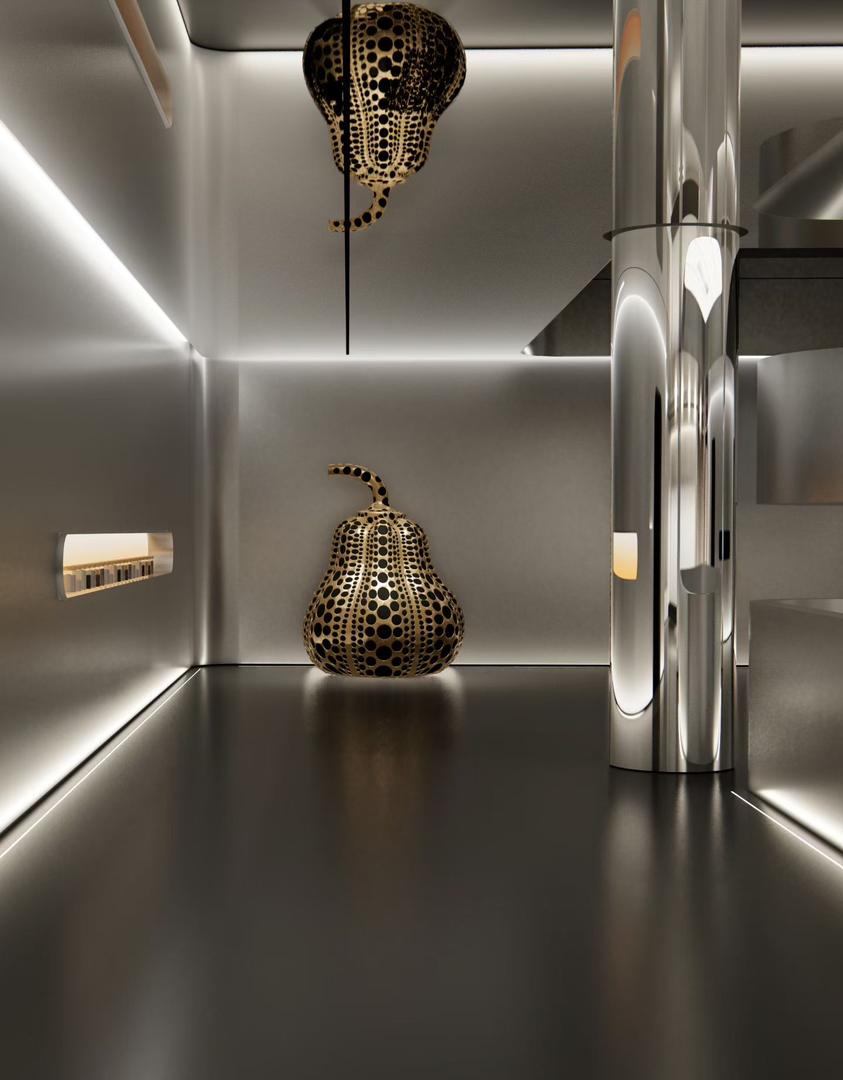 Apple sand stainless steel showroom wall with warm LED cove lighting at floor and ceiling, a mirror polished column and a gold and black spotted sculpture