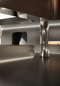 Brushed stainless steel reception desk with LED glow at its base, a mirror polished column and a backlit portal in a luxury showroom