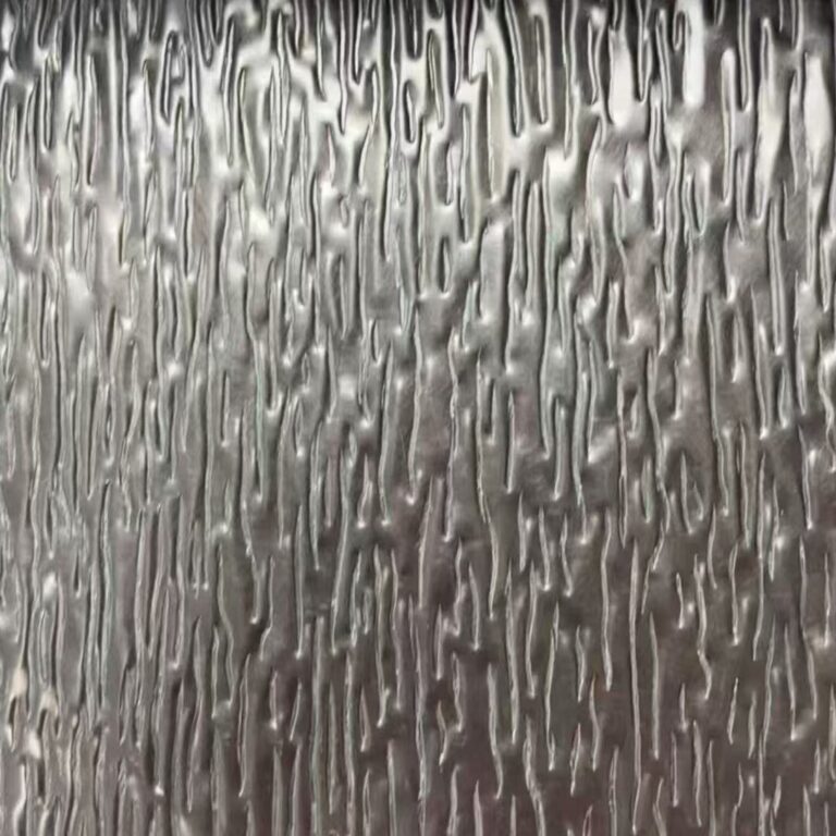 Close-up of a stainless steel sheet embossed with a tree bark relief, showing dense irregular vertical grooves that break the surface into ridges and hollows