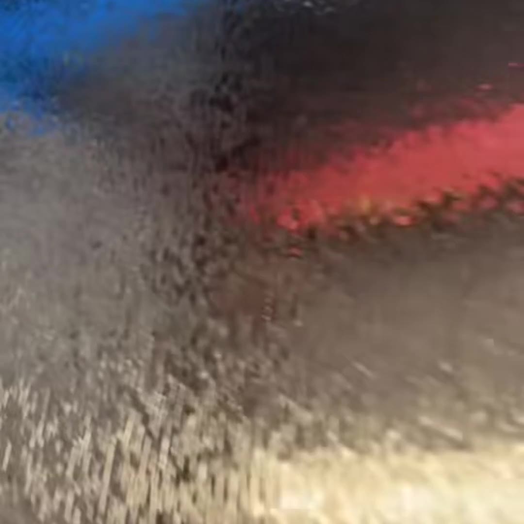 Macro frame from the film: blue and red light reflected in the polished hollows of the bark texture, showing how the relief picks up coloured light from its surroundings