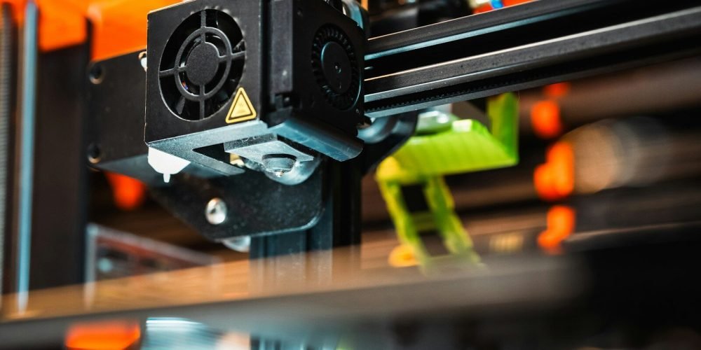A 3D printer is shown in close-up detail.